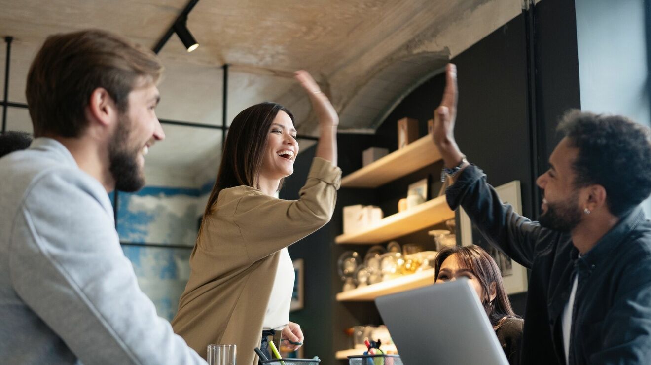 Two cheerful young business people giving high-five while their 